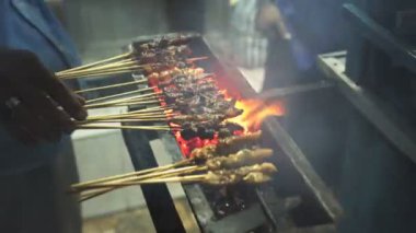 Bir aşçı kuta, bali 'de bir sokakta et şişi hazırlar.