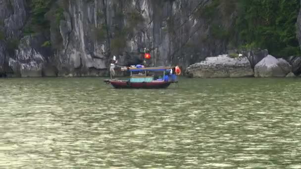 Mediumbild av en vietnamesisk fiskebåt vid foten av klippor i halongviken — Stockvideo