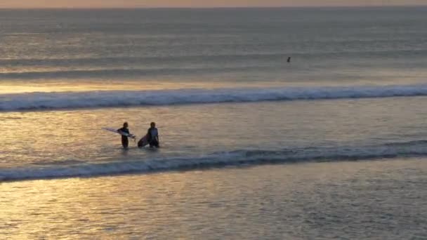 Due surfisti che entrano dopo aver fatto surf sulla spiaggia di kuta, bali — Video Stock