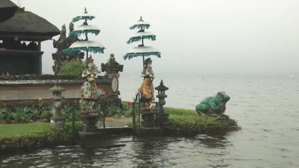 Две статуи многообразия и большая статуя лягушки ulun danu beratan храм, бал — стоковое видео