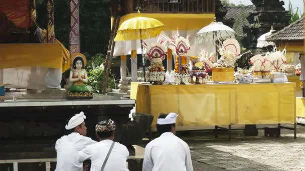 TABANAN, INDONESIA- JUNE, 16 2017: three devotees sit and worship at ulun danu bratan temple, bali — Stock Video