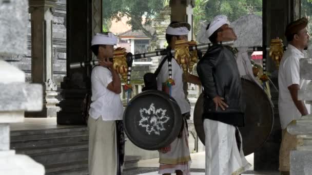 TABANAN, INDONESIA- JUNI, 16 2017: muzikanten dragen en spelen een grote gong in de ulun danu bratan tempel — Stockvideo