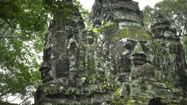 Tiro de ângulo baixo de uma torre de rosto coberta de líquen em angkor wat — Vídeo de Stock