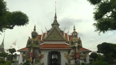 Bangkok 'taki Wat Arun tapınağında iki dev iblis heykelinin yanından geçerken üç eksenli vibratör atışı.