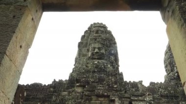 Düşük açılı taş yüz kulesi. Bayon Tapınağı 'nda bir kapı aralığı tarafından çerçevelenmiş.
