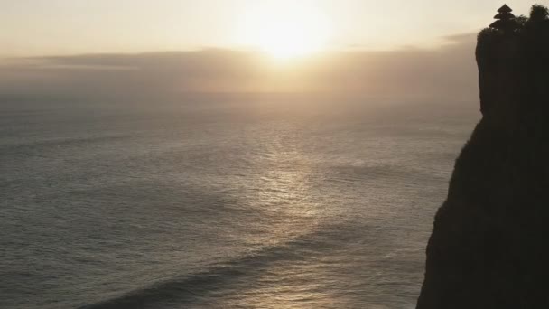 バリ島の夕日に波が打ち寄せるウルワツ寺の近景 — ストック動画
