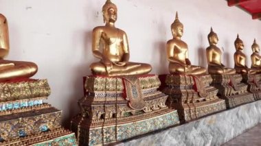 Bangkok 'taki Wat Po Tapınağı' ndaki manastırda Buda heykellerinin yanından geçiyorum.