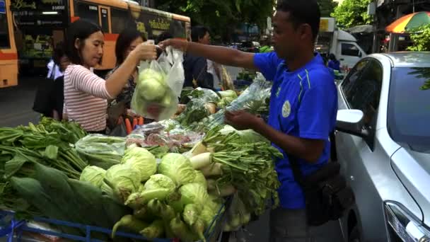 BANGKOK，THAILAND-JUNE，2017年6月21日：一个男人在唐人街的推车上卖蔬菜给顾客 — 图库视频影像