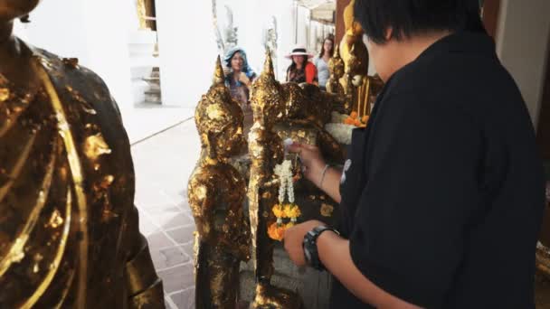 BANGKOK, Tajlandia - czerwiec, 21, 2017: Tajka kobieta dodaje złoty liść do posągu w świątyni Wat pho w Bangkoku — Wideo stockowe