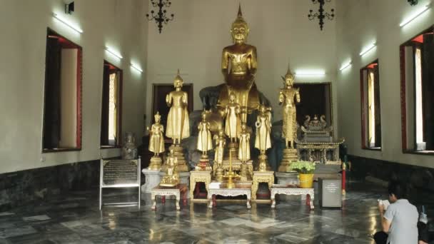 BANGKOK, THAILANDIA-GIUGNO, 21, 2017: una donna thai legge e adora davanti alle statue in un tempio WAT Pho — Video Stock