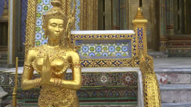 Tiro de uma estátua de anjo dourado na entrada lateral do templo de buddha dourado em bangkok — Vídeo de Stock