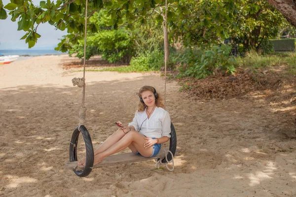 Menina sentada no balanço na praia tropical, ilha paradisíaca Fotos De Bancos De Imagens Sem Royalties