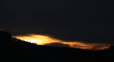 Günbatımı kırmızı yaz köyde ağaçların arkasında .