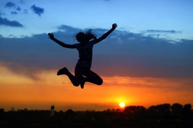 Neşeli atletik kız güzel kırmızı günbatımı arka planı için pratik yapıyor..