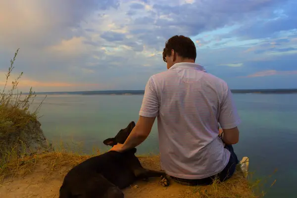 Homem e cão sittig na rocha — Fotografia de Stock