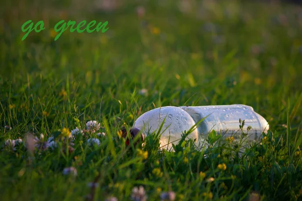 Пластиковая бутылка на фоне зеленой травы — стоковое фото