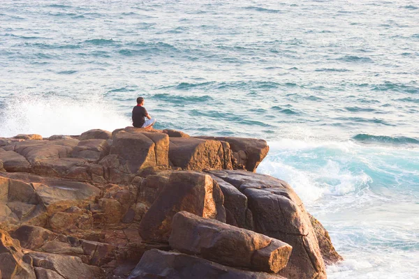 Az ember meditál egy sziklán a tengernél. — Stock Fotó