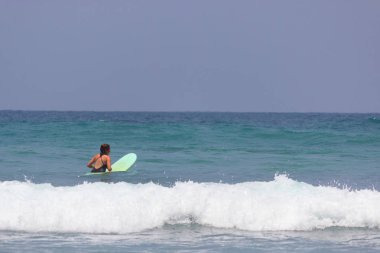 Bikini kız eğlenceli sörf tahtası üzerinde vardır.