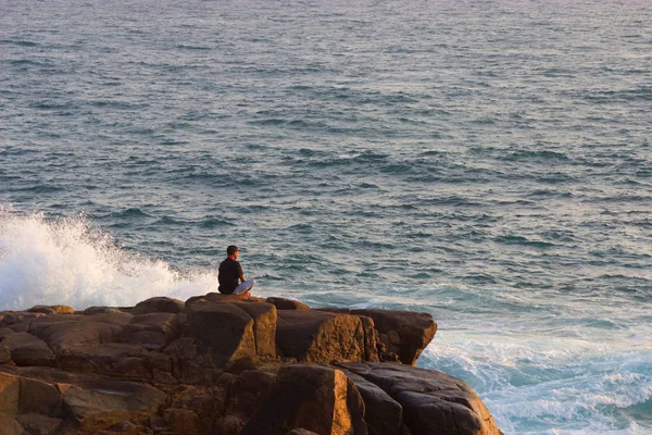 Ο άνθρωπος διαλογίζεται σε ένα βράχο στη θάλασσα — Φωτογραφία Αρχείου