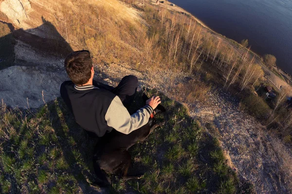 Homem e cão sentados na agde da colina — Fotografia de Stock