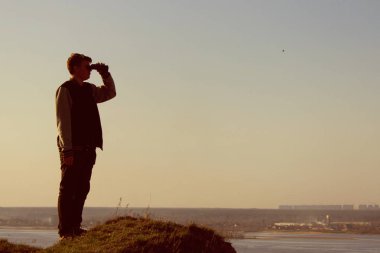 dağlarda dürbün ile bakan genç adam