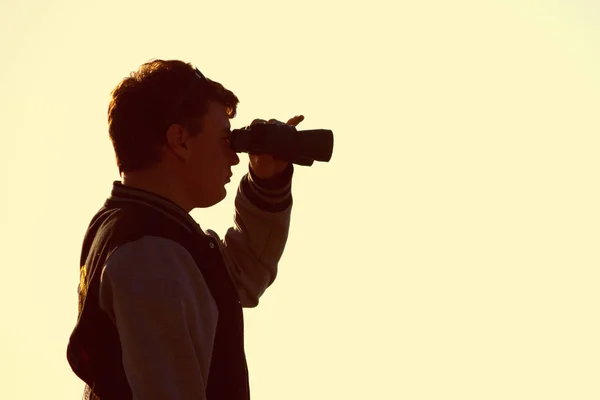 Silhouette of man watching sunset with binoculars — Stock Photo, Image