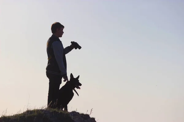 Homem e seu carrinho de cão no pico da montanha — Fotografia de Stock
