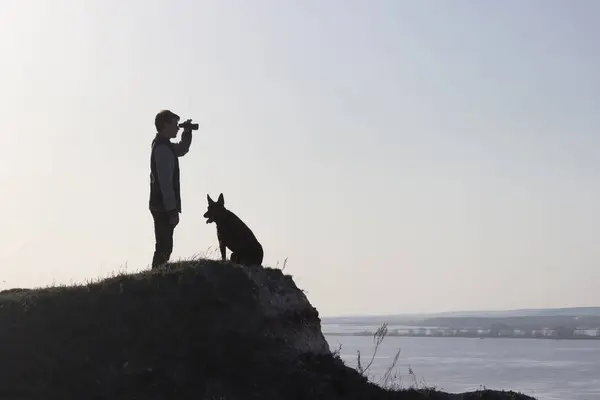 Uomo e il suo cane stanno sulla vetta della montagna — Foto Stock