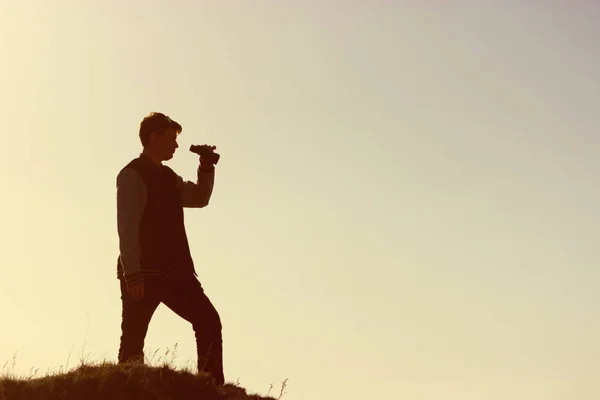 Jovem olhando através de binóculos nas montanhas — Fotografia de Stock