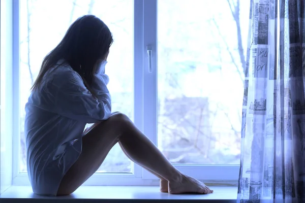 Roztomilý smutná dívka u okna doma — Stock fotografie