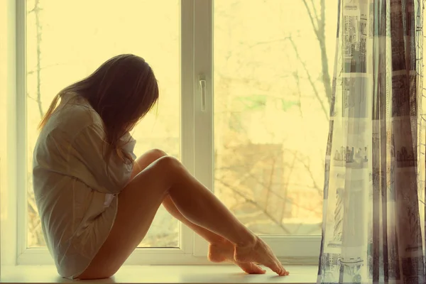 Carino ragazza triste vicino alla finestra a casa — Foto Stock