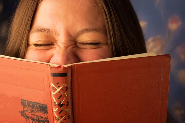 Frau liest Buch zu Hause und lacht — Stockfoto