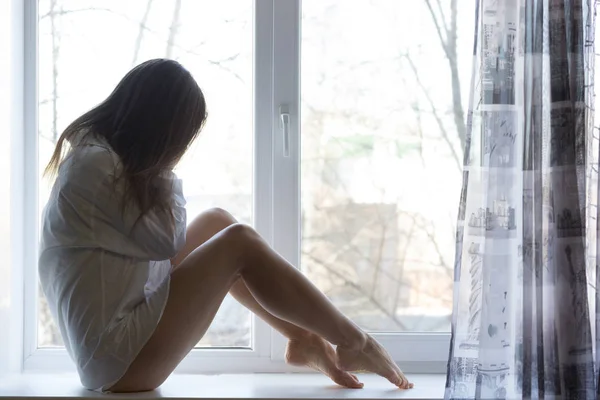 Милая грустная девушка у окна дома — стоковое фото