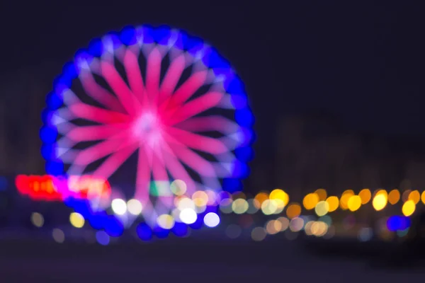 Roda gigante desfocada com luzes coloridas — Fotografia de Stock