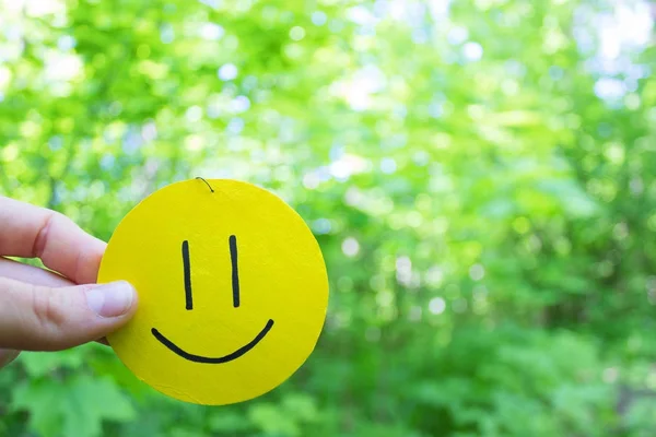 Sorriso amarelo no fundo folhas verdes — Fotografia de Stock