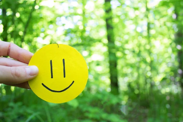 Sorriso amarelo no fundo folhas verdes — Fotografia de Stock