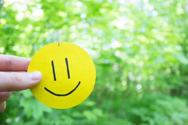 Sorriso amarelo no fundo folhas verdes — Fotografia de Stock