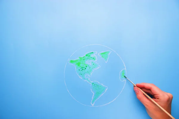 Рука з пензлем карта світу в зеленому кольорі — стокове фото