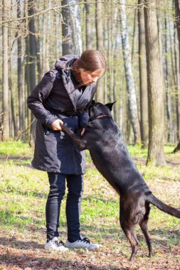genç kadın oyun ile bir parkta siyah köpek