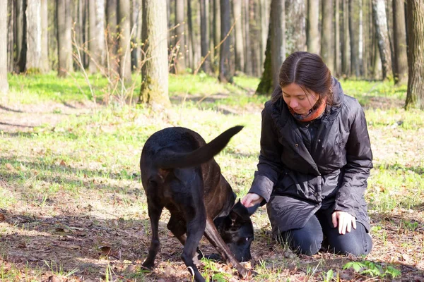 genç kadın oyun ile bir parkta siyah köpek