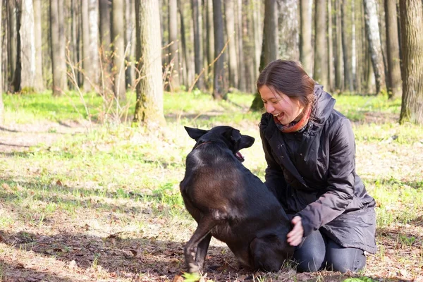 genç kadın oyun ile bir parkta siyah köpek