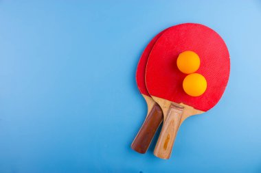 Masa tenis raketleri ve topları mavi zemin üzerine
