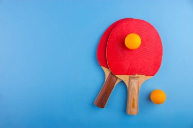 Masa tenis raketleri ve topları mavi zemin üzerine