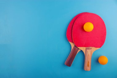 Masa tenis raketleri ve topları mavi zemin üzerine