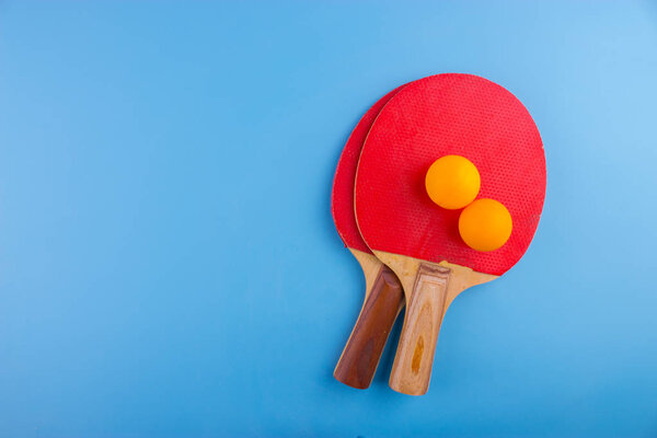 Table tennis rackets and balls on blue background