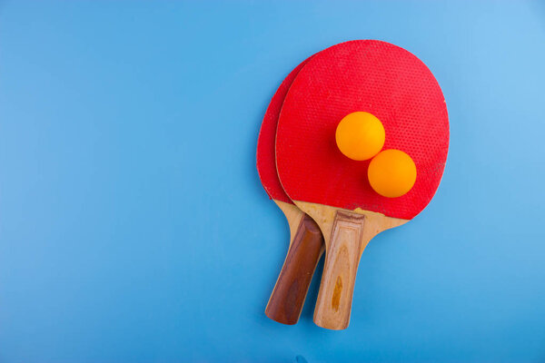 Table tennis rackets and balls on blue background