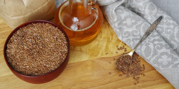 Semillas de lino en cuchara y en tazón de madera. Aceite de linaza en jarra de vidrio — Foto de Stock