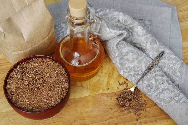 Semillas de lino en cuchara y en tazón de madera. Aceite de linaza en jarra de vidrio — Foto de Stock