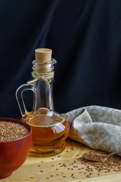 Semillas de lino en cuchara y en tazón de madera. Aceite de linaza en jarra de vidrio — Foto de Stock