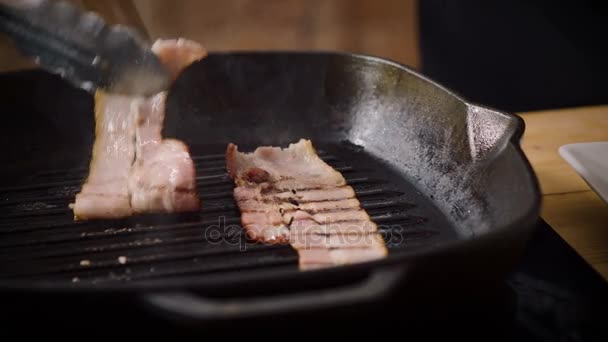 The cooks hand putting two pieces of fried bacon from the broiler pan on a white plate. 4K — Stock Footage The cooks hand putting two pieces of fried bacon from the broiler pan on a white plate. 4K Royalty Free Stock Footage